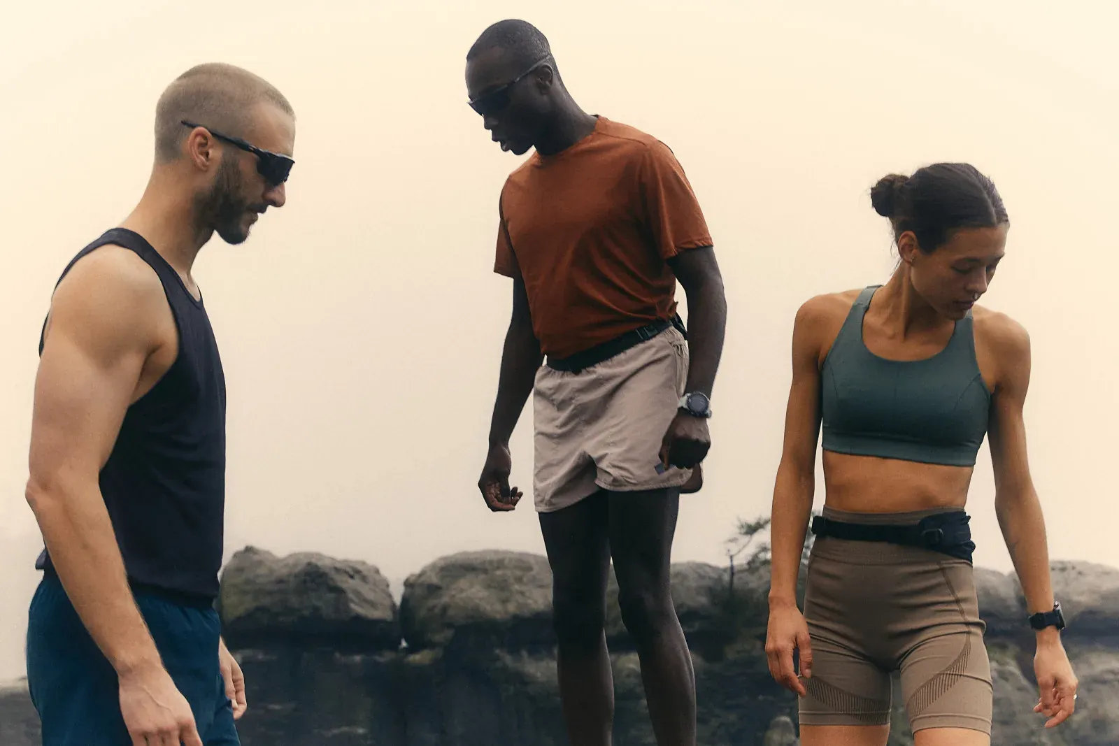 Three people in activewear outdoors on a rocky headland.